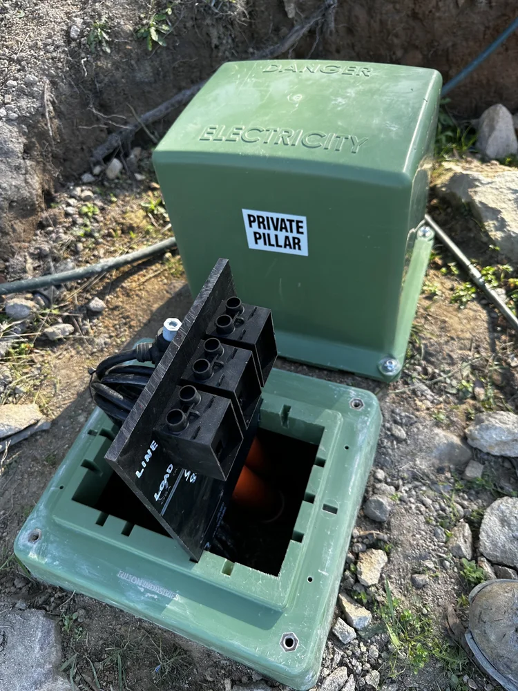 Outdoor electrical box with a green cover labelled danger