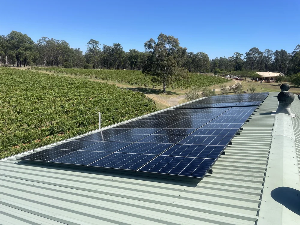 Solar panels installed on a metal roof overlooking green fields