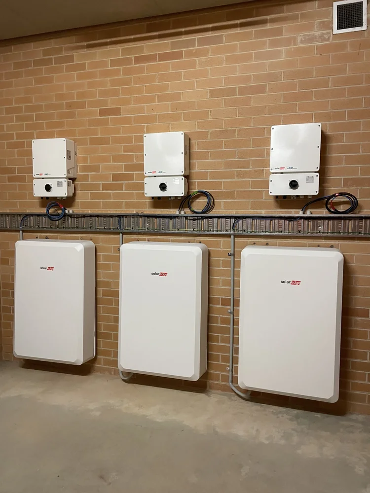 Two solar power inverters mounted on a brick wall