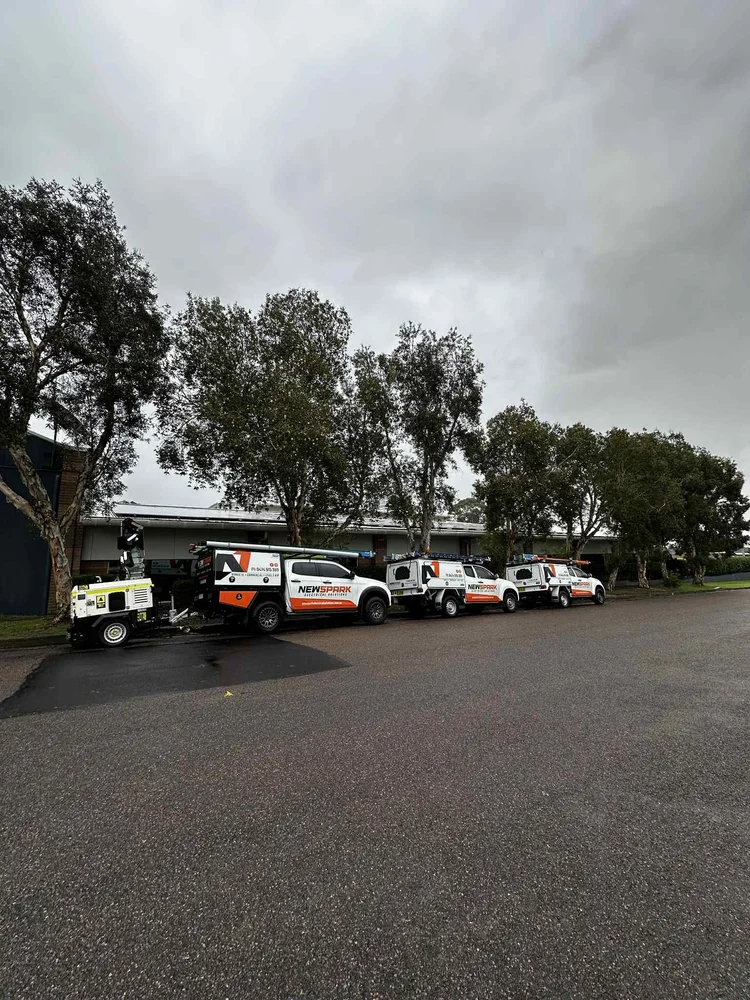 Three utility trucks parked in a row on wet asphalt