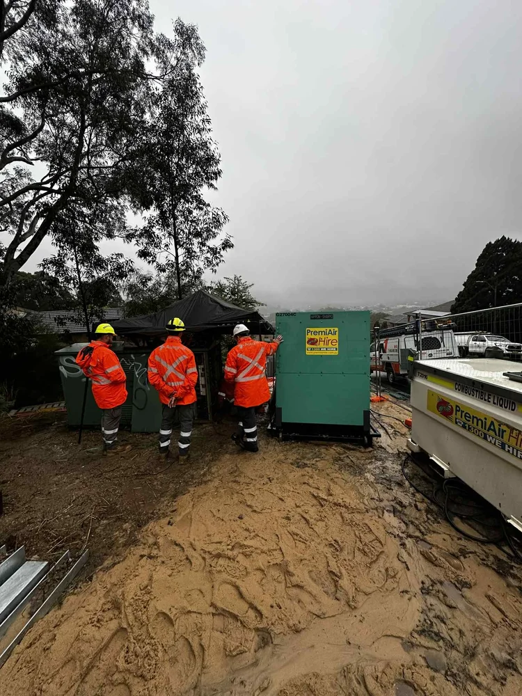 Three NewSpark workers in hi-vis jackets and helmets beside the truck