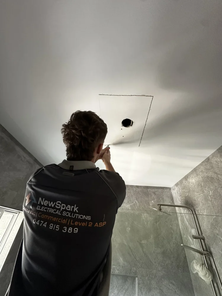 An electrician working on a ceiling wiring installation